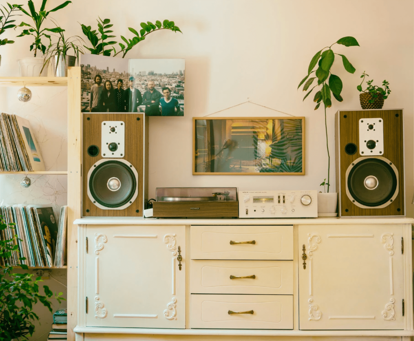 cream furniture with green plants surrounding it record player and wood-paneled stereo system